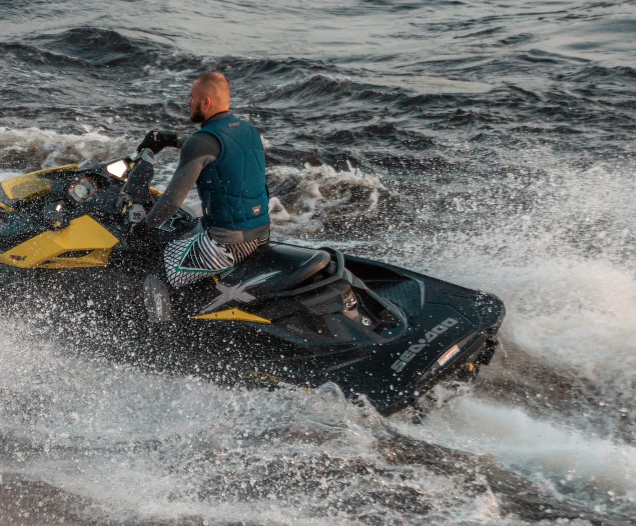 Un jet-ski de trois quarts au virage, gerbe d'eau derrière