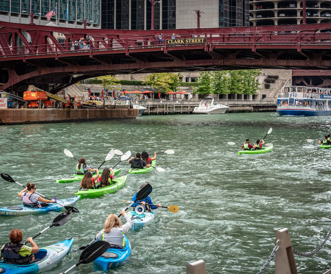 Un groupe de kayaks de couleur sur la rivière, sous un pont
