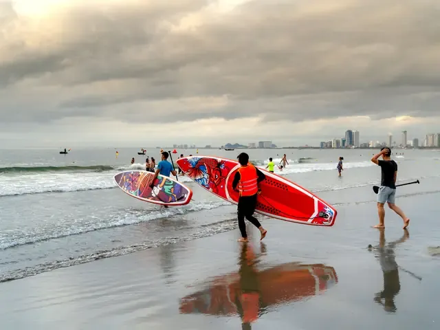 Un groupe porte des planches de paddle rouges vers l'eau