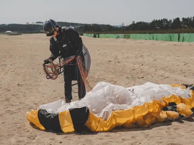 Une voile étalée au sol, en cours de pliage après l'atterrissage